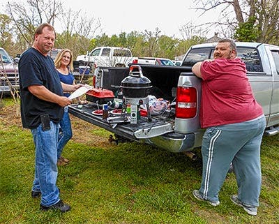 Three people standing around, grilling burgers, tailgating at the turkey shoot